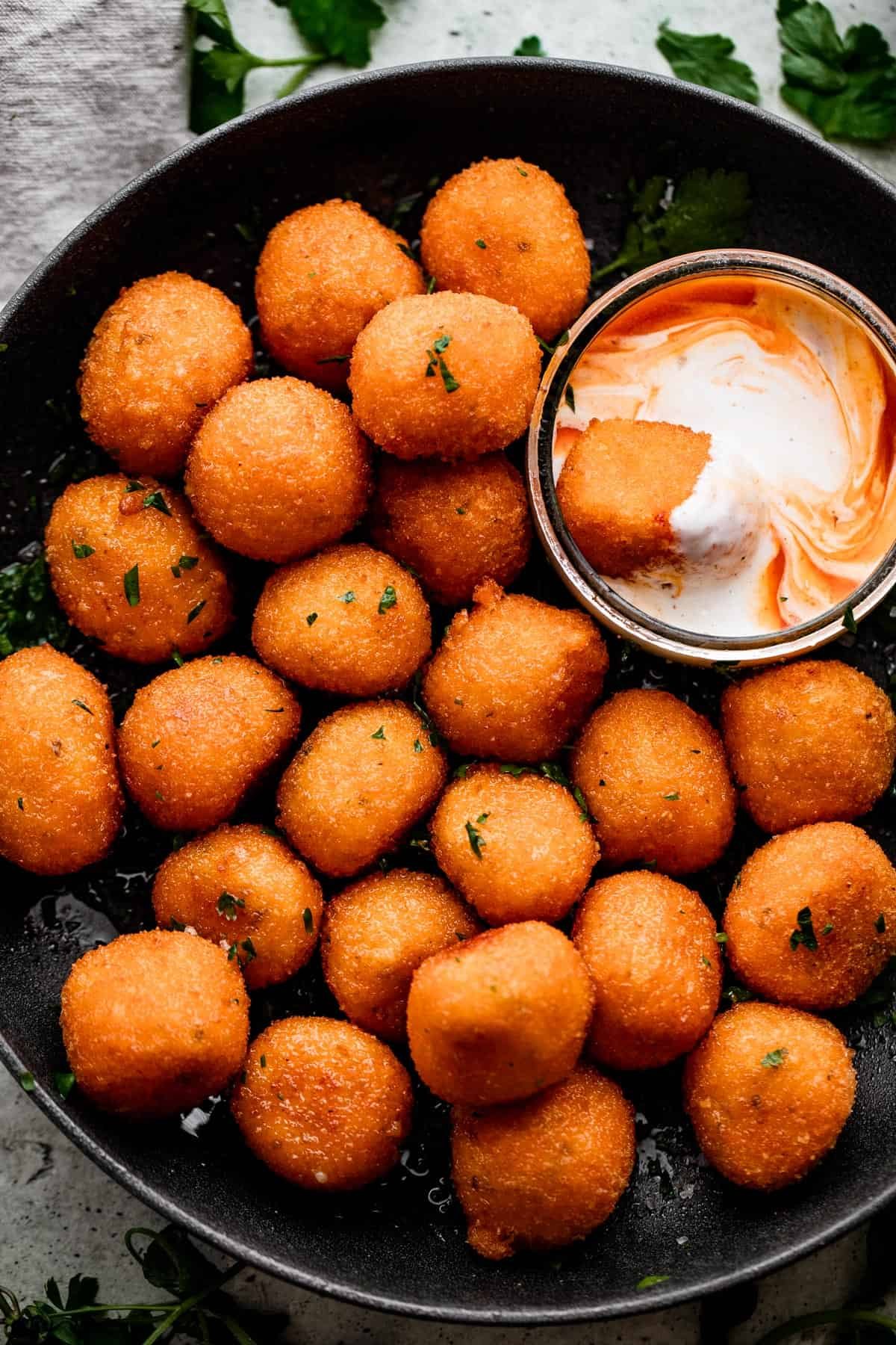 overhead shot of Jalapeno Popper Balls in a black bowl with a Dipping Sauce