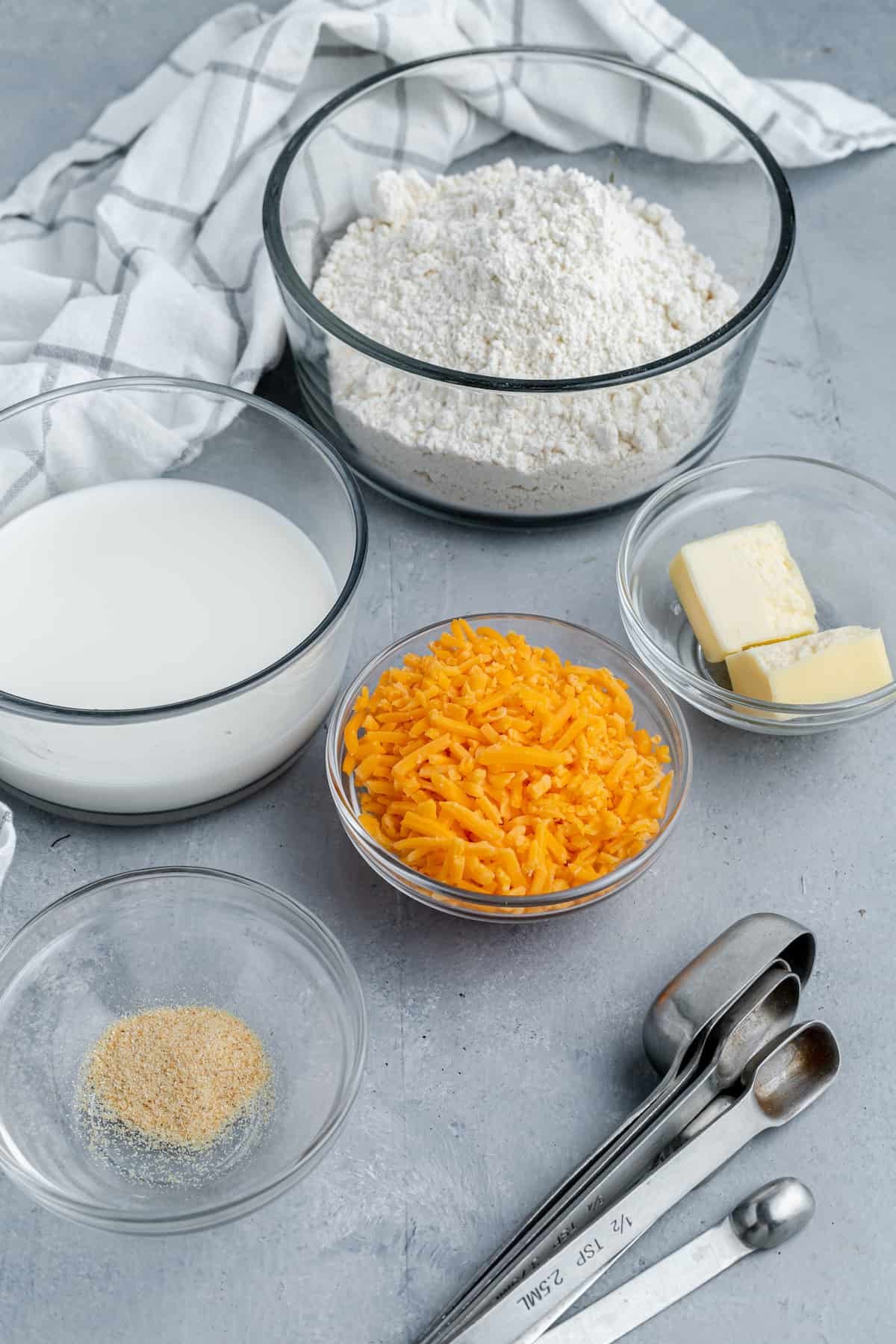 Bisquick, Butter, Garlic Powder, Shredded Cheese and the Rest of the Recipe Ingredients on a Gray Countertop