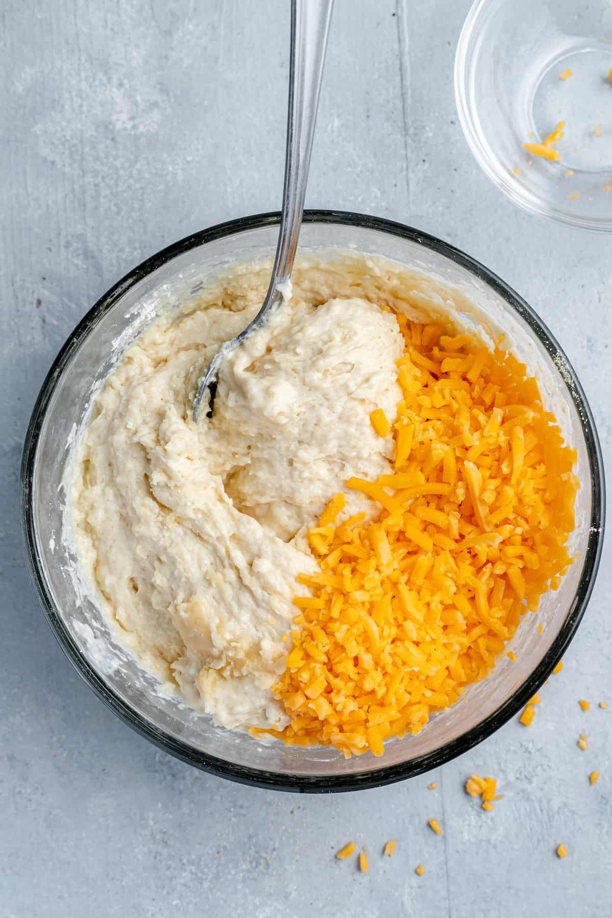Shredded Cheddar Cheese Being Mixed Into the Biscuit Batter with a Spoon