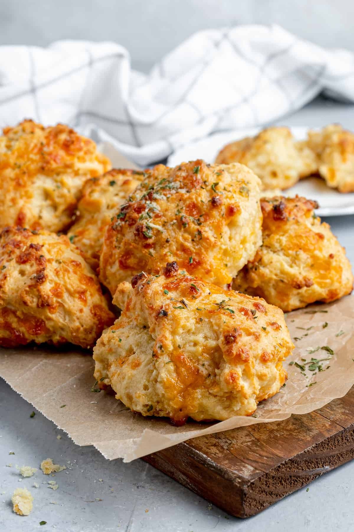 Six Air Fryer Biscuits on a Piece of Parchment Paper Over a Wooden Board