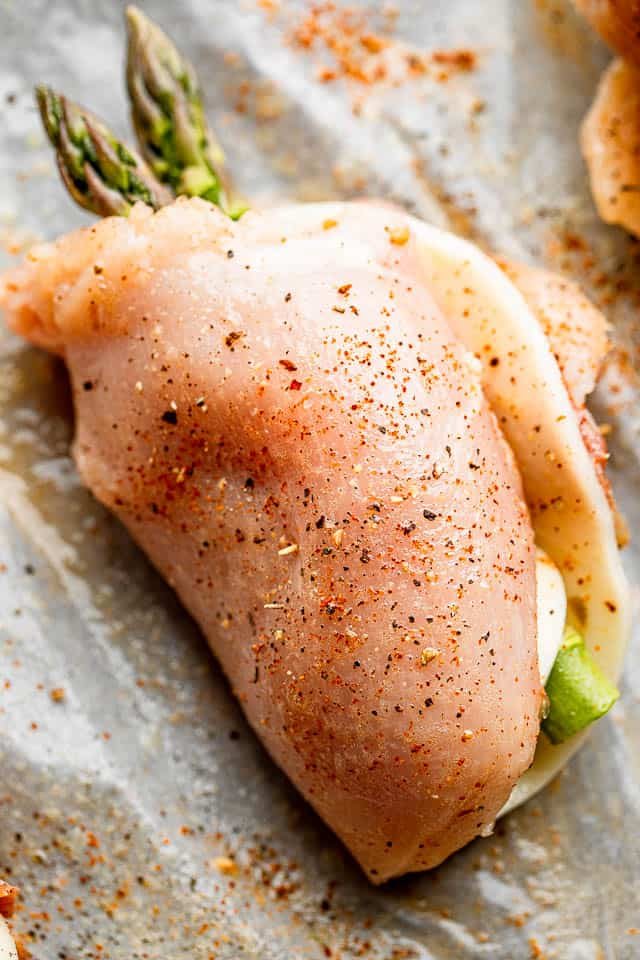 raw chicken breast rolled up with asparagus spears and cheese slice