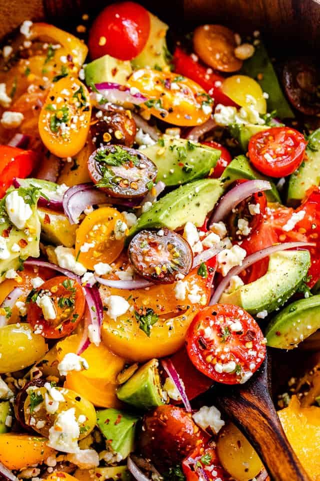 close up top shot of a salad with cherry tomatoes, heirloom tomatoes, avocado, and crumbled bleu cheese