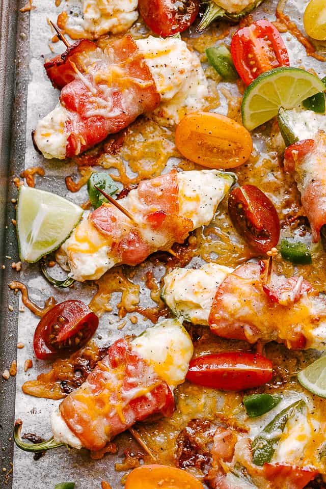 Baked, bacon-wrapped jalapeno poppers on a parchment-lined baking sheet.