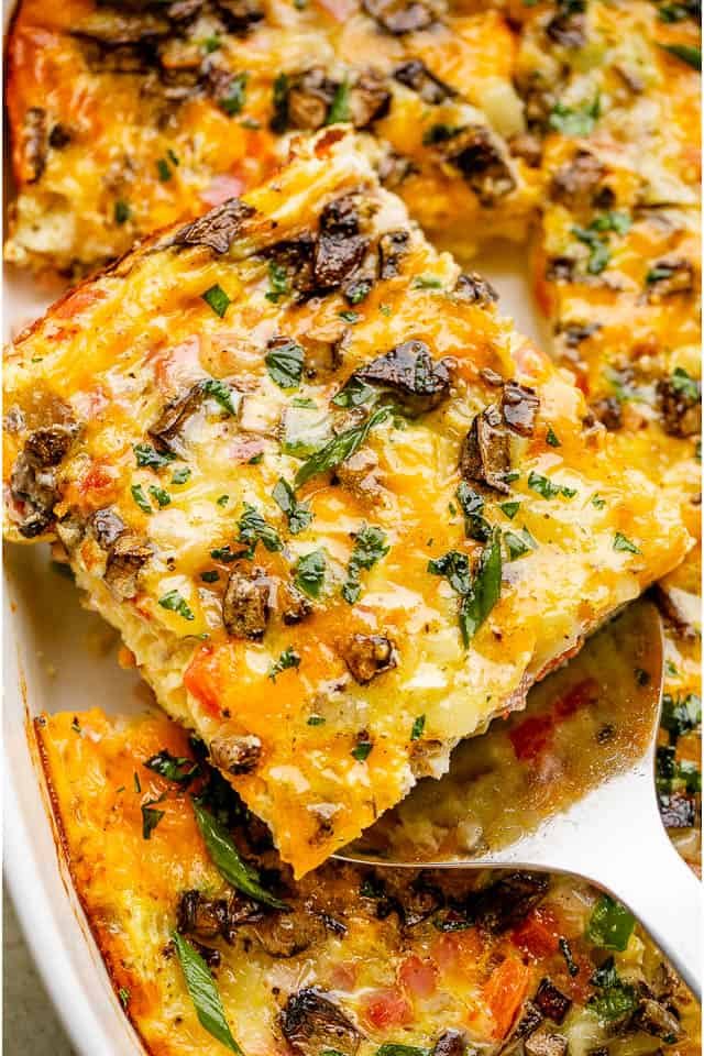 Serving a slice of Baked Denver Omelette topped with fresh parsley.