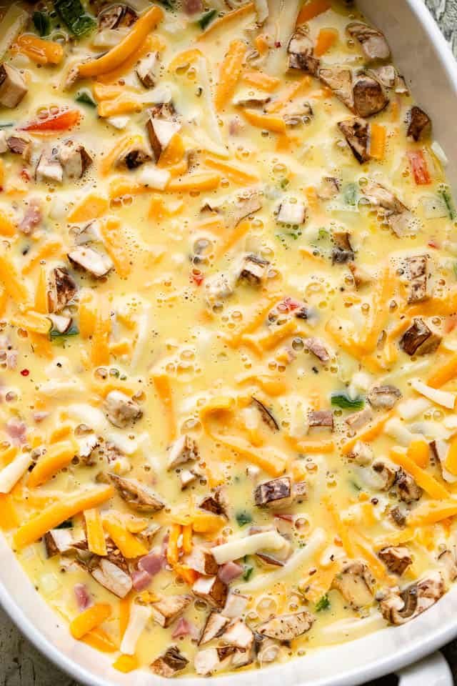 Peppers, onions, eggs, and cheese in a baking dish ready for the oven.