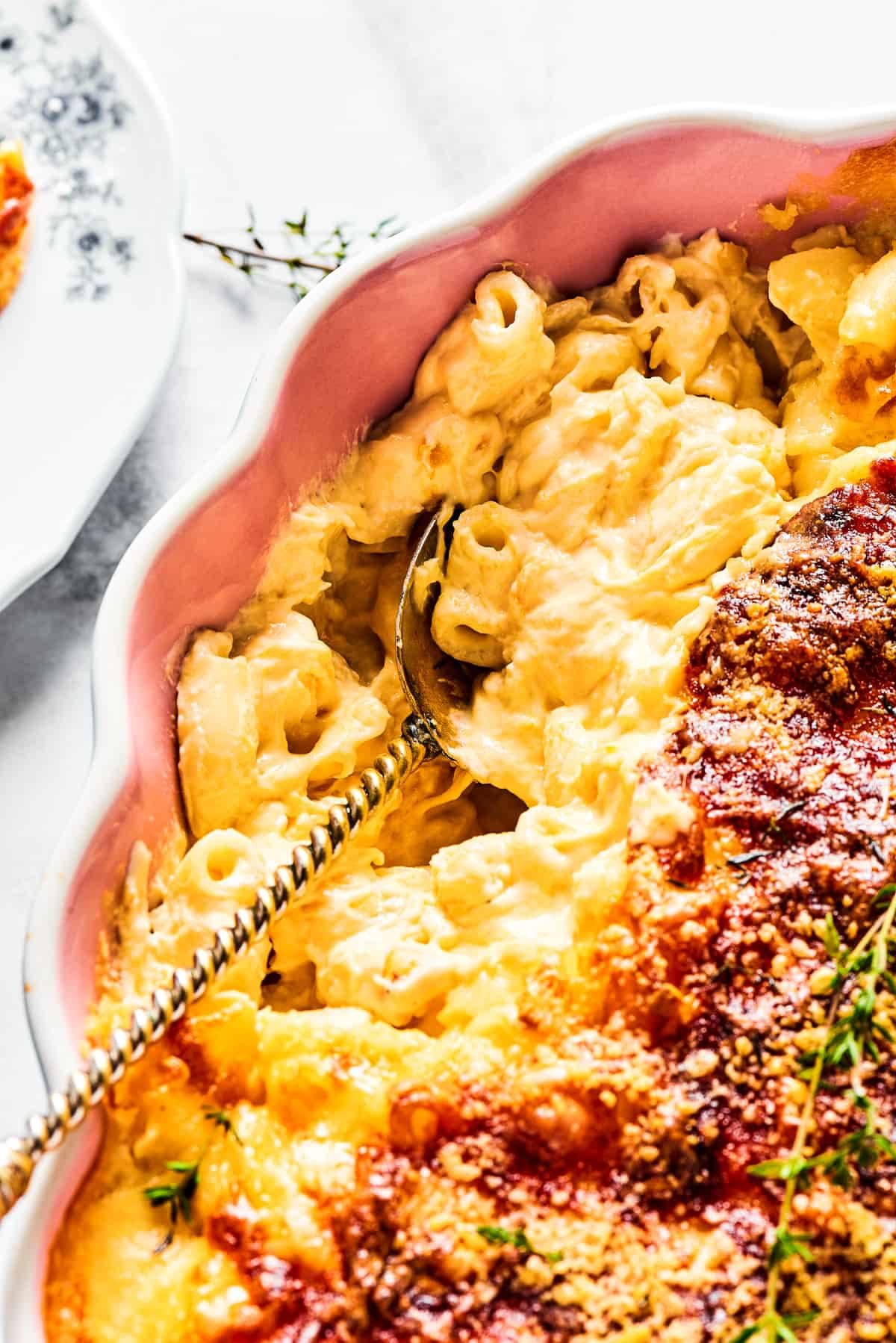 Spooning baked macaroni out of a casserole dish.