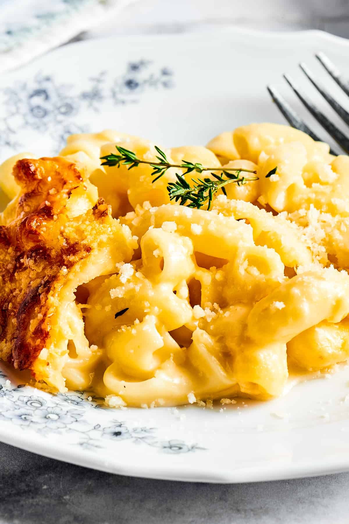 Macaroni and cheese garnished with fresh herbs on a flowered plate.