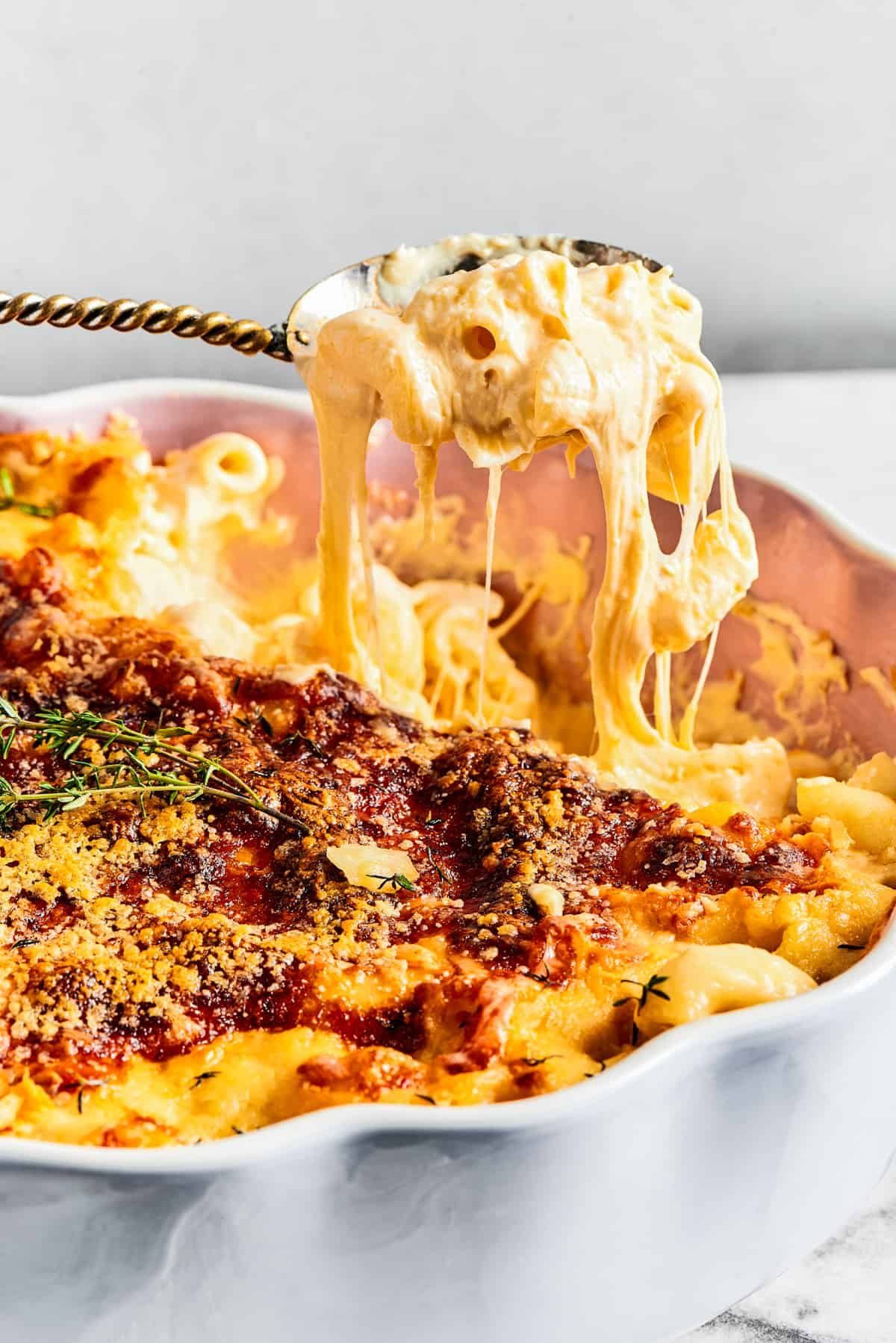 Lifting a spoonful of mac and cheese out of a fluted baking dish.