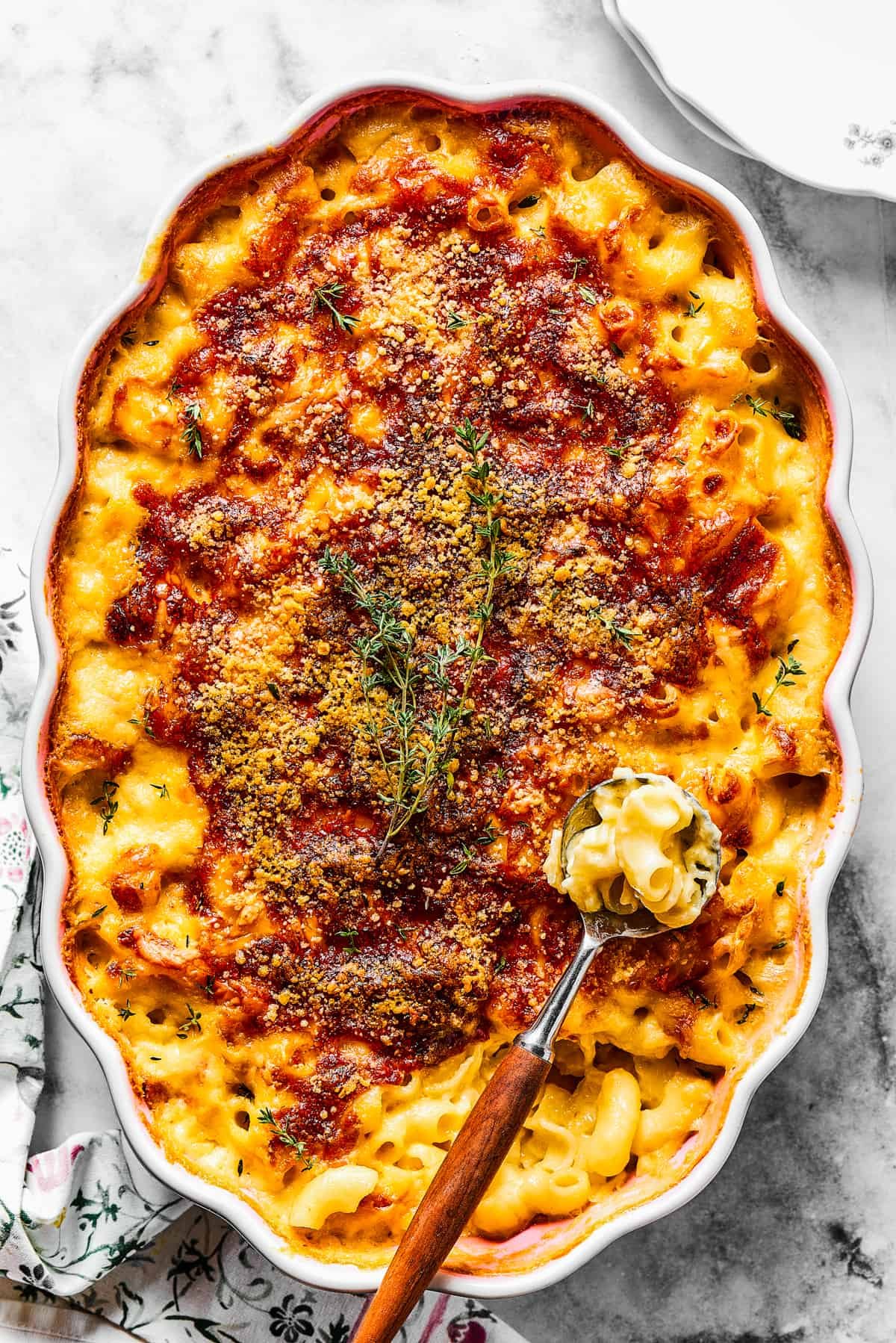 Spooning baked macaroni out of a casserole dish.