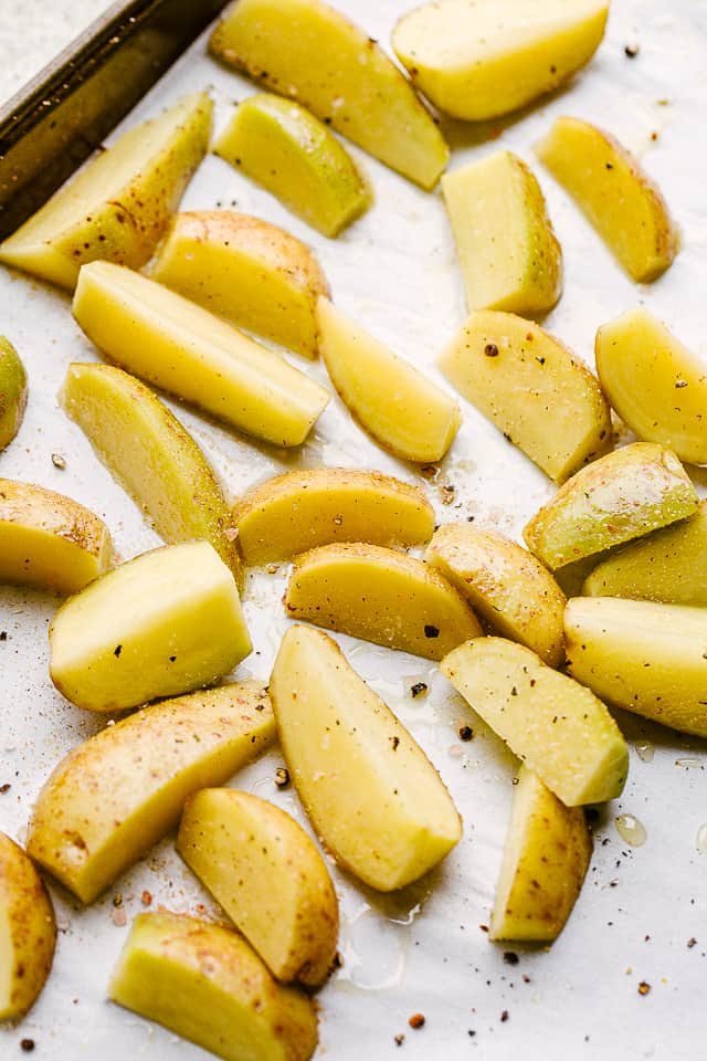 Seasoning potatoes before putting them in the oven.