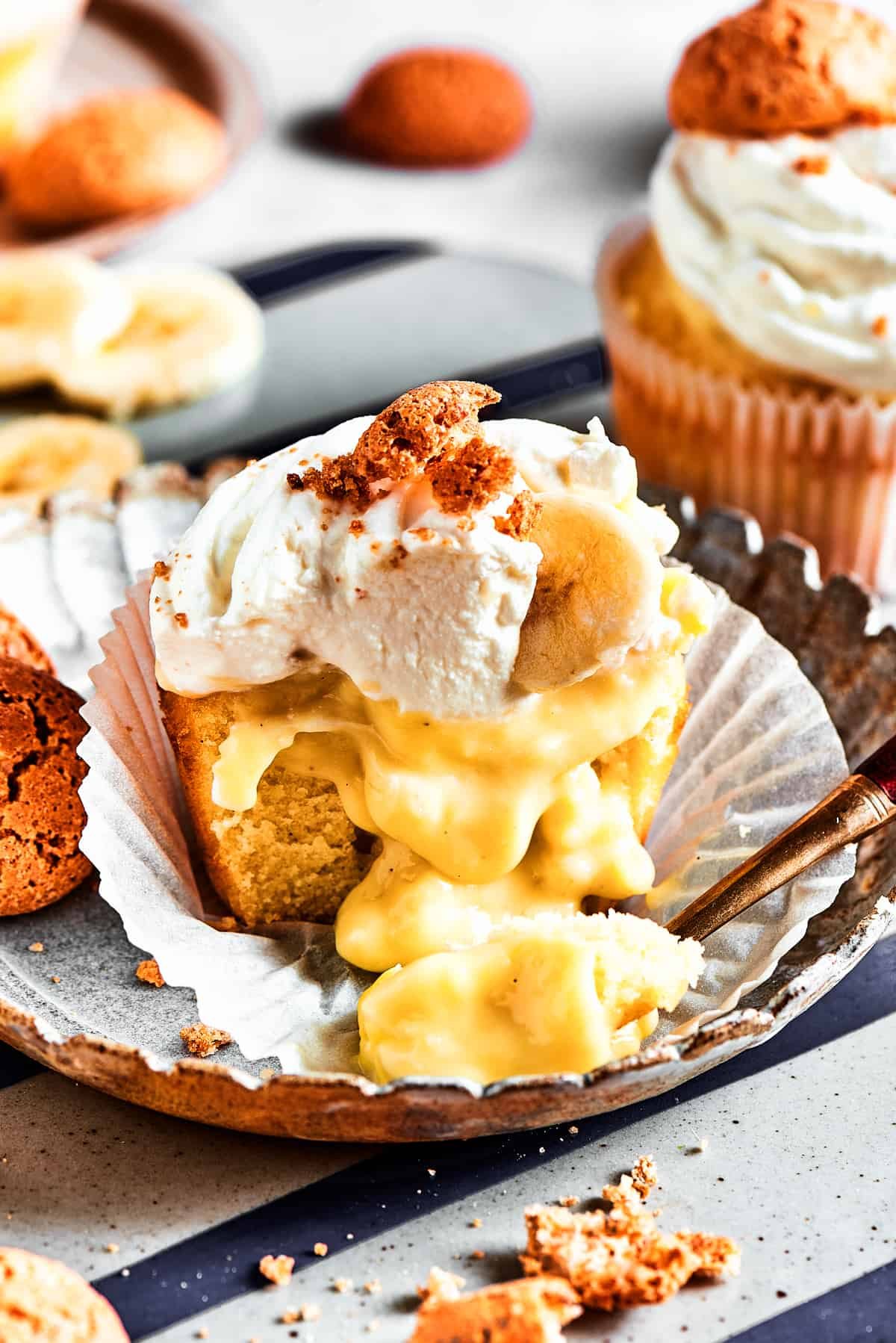 A halved cupcake with the wrapper pulled down, showing the banana pudding filling dripping out.