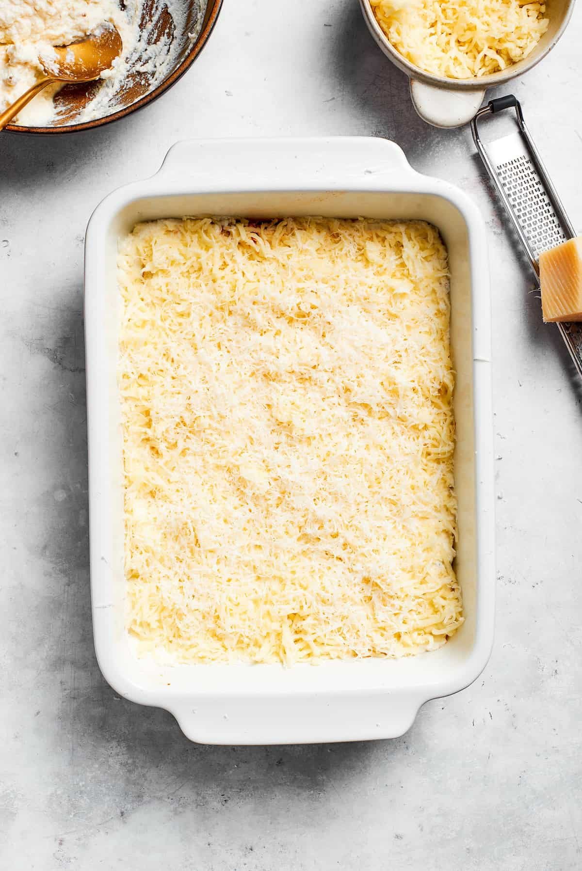Shredded cheese is added to the ricotta layer.