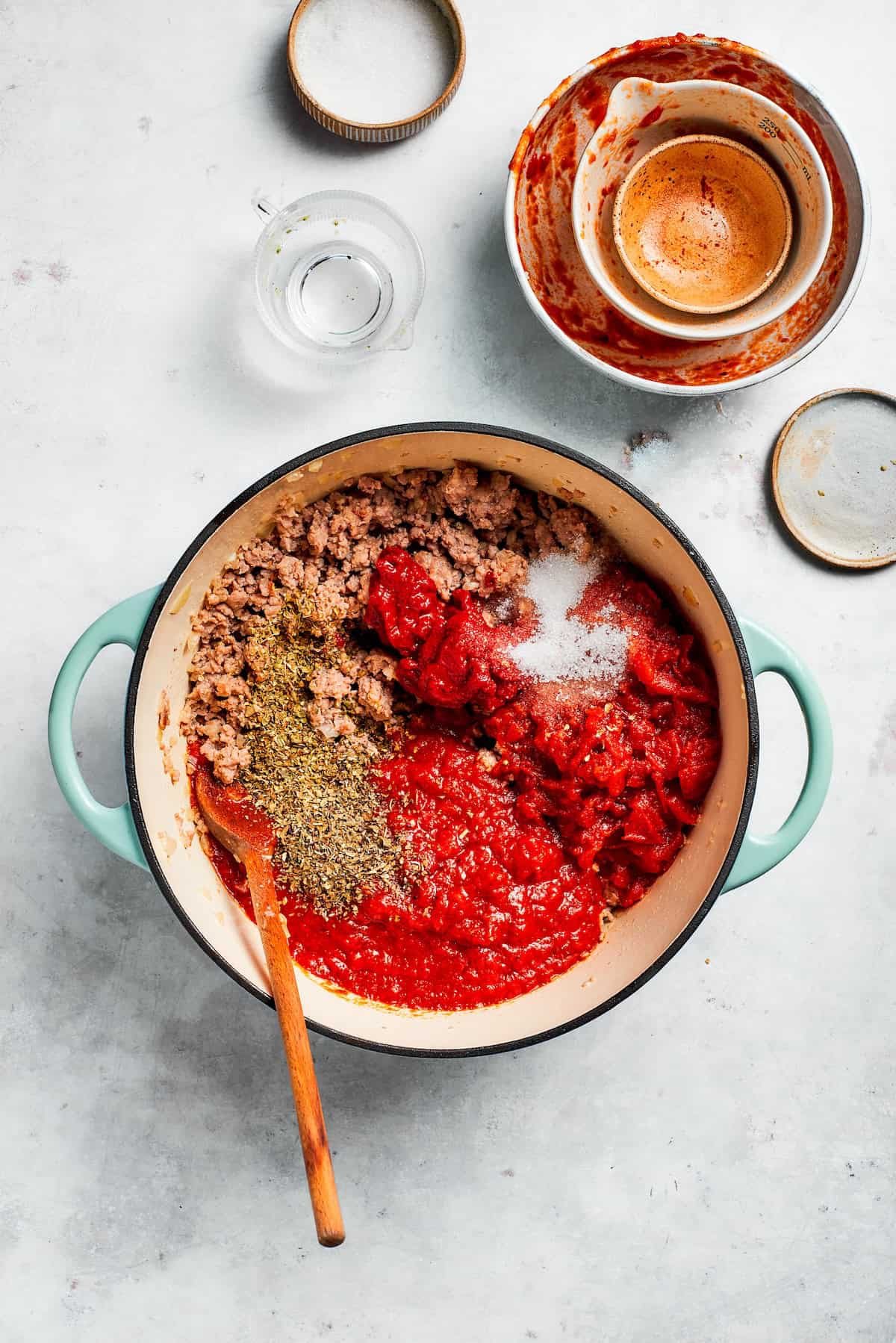 Sauce and tomato paste are added to a skillet.