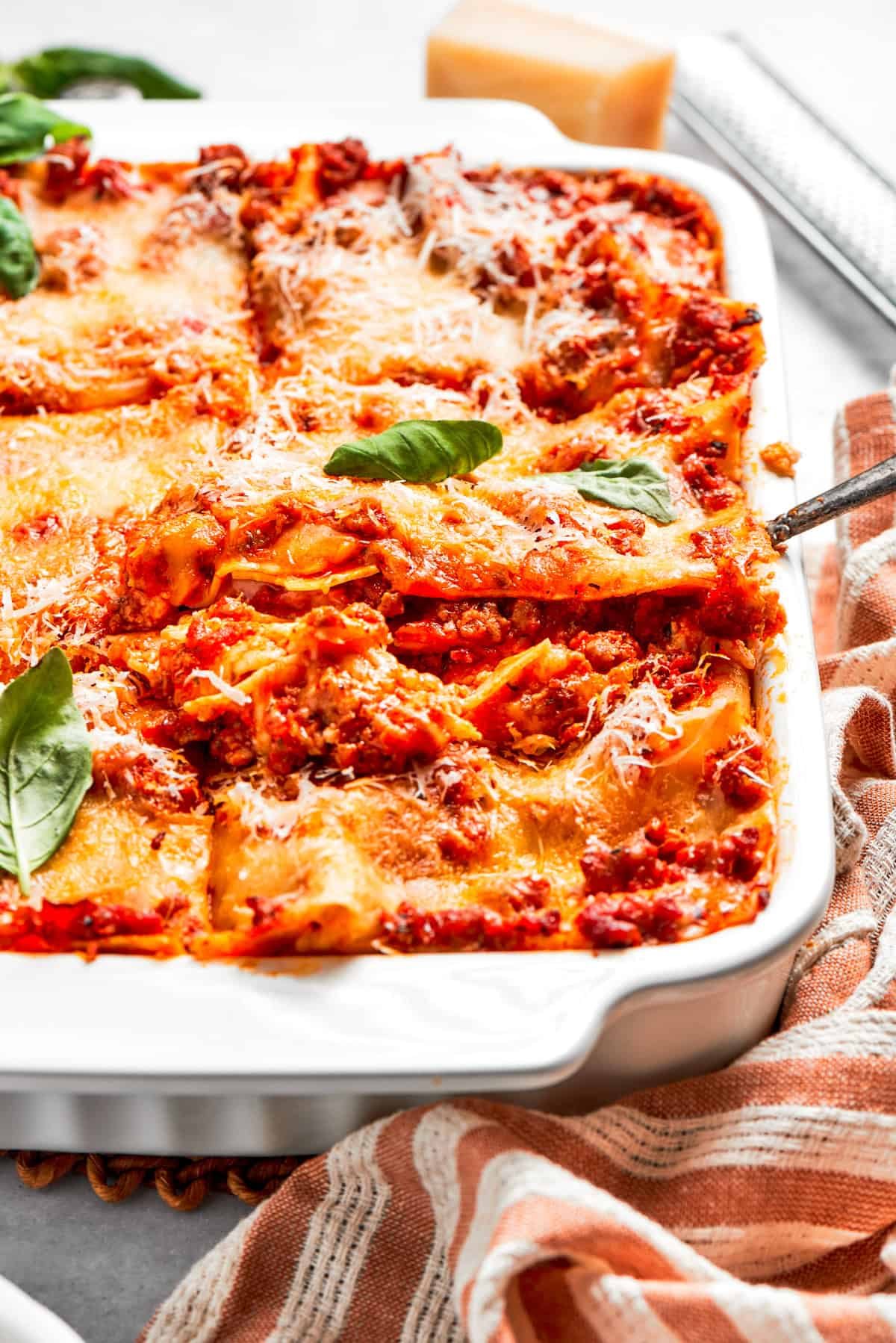Lifting out a slice of lasagna from a baking dish.