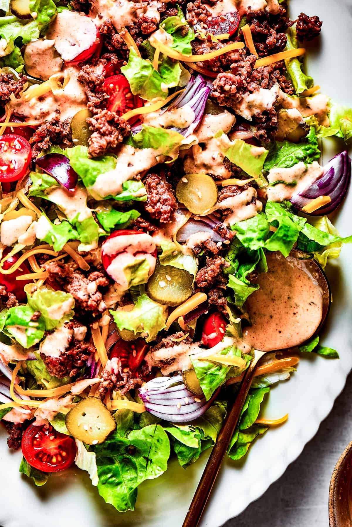 Close-up of a Big Mac Salad with red onion, ground beef, shredded cheese, and more.