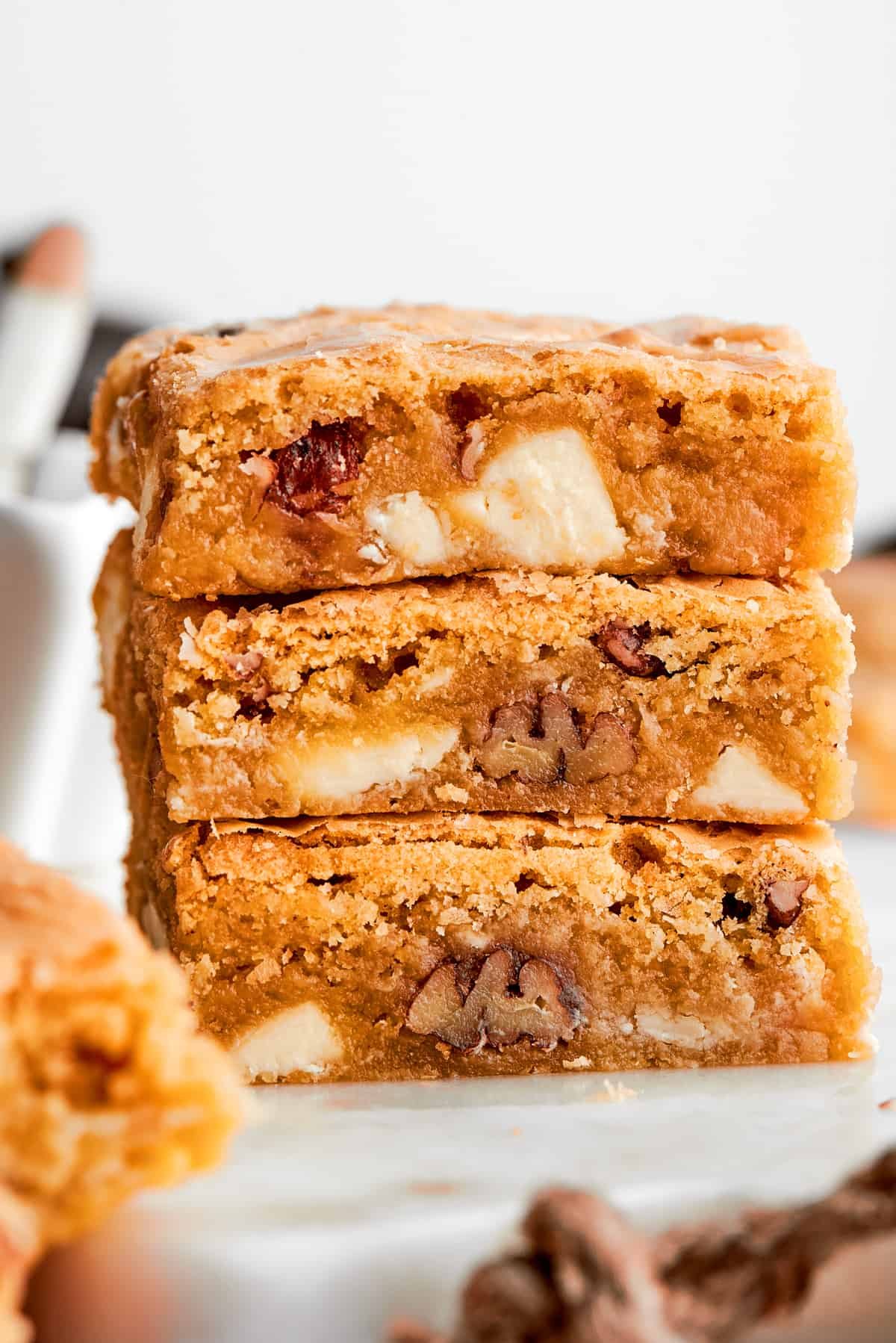A stack of three blonde brownies with white chocolate chips and pecans visible.