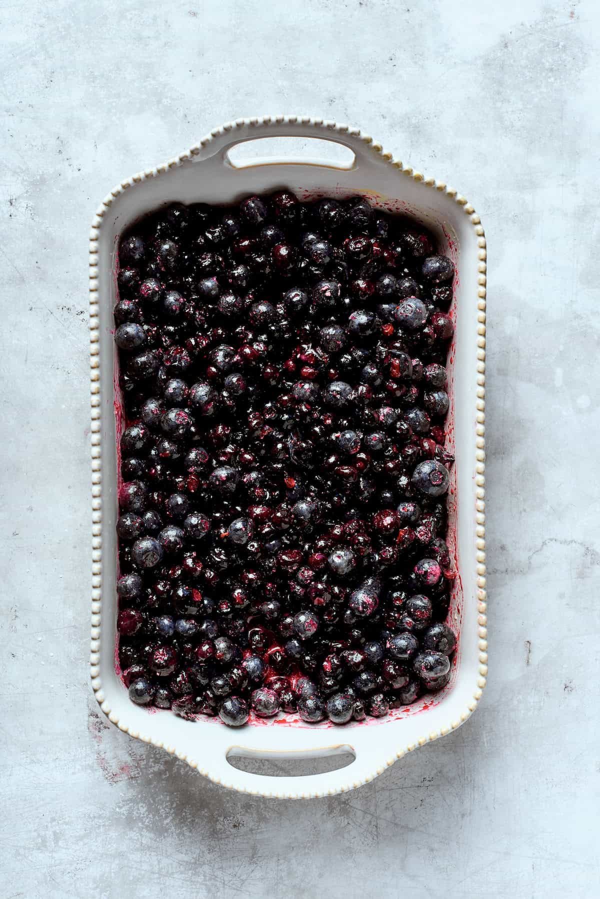 The filling for blueberry crisp is spread out in a pan.