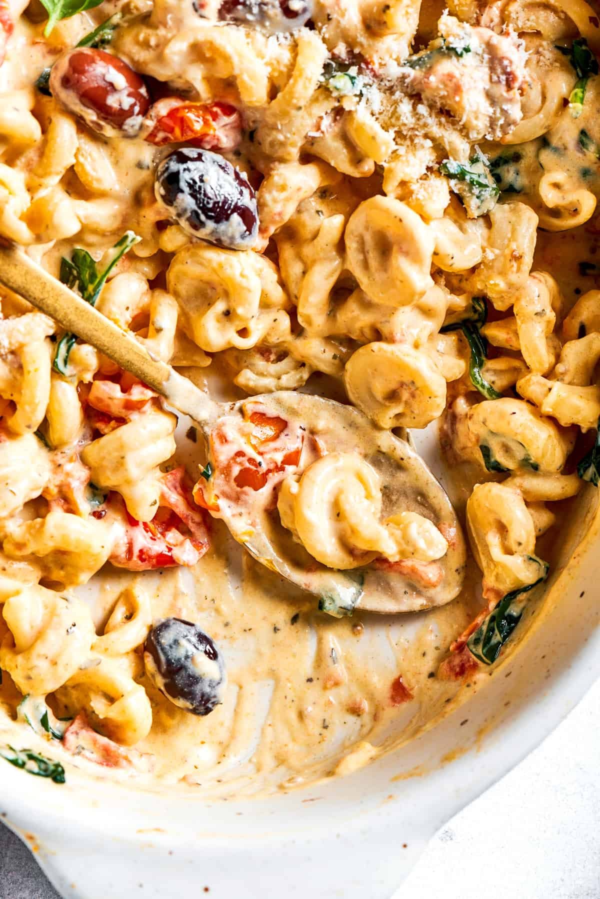 Spooning out Boursin pasta from a baking dish.