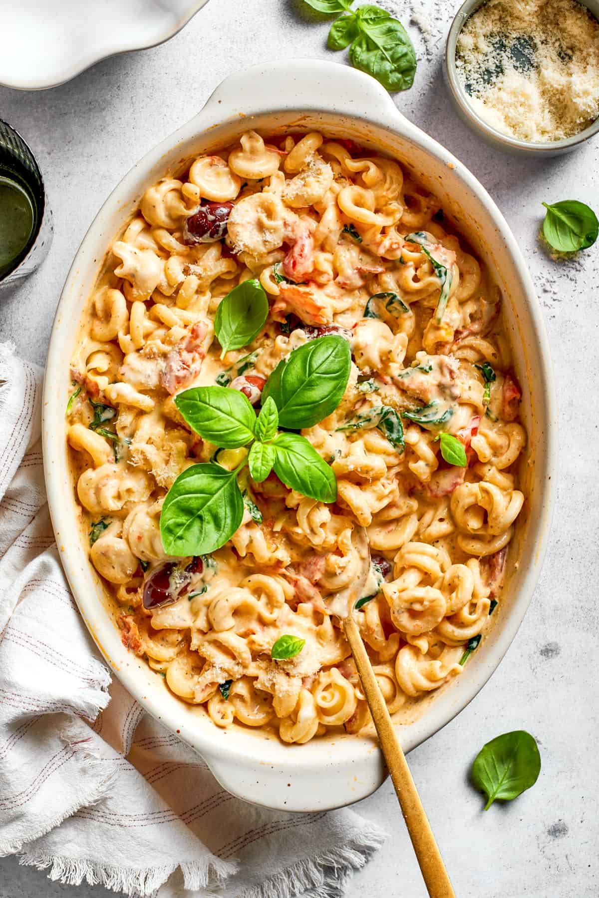 Baked pasta in a casserole dish garnished with fresh basil leaves.
