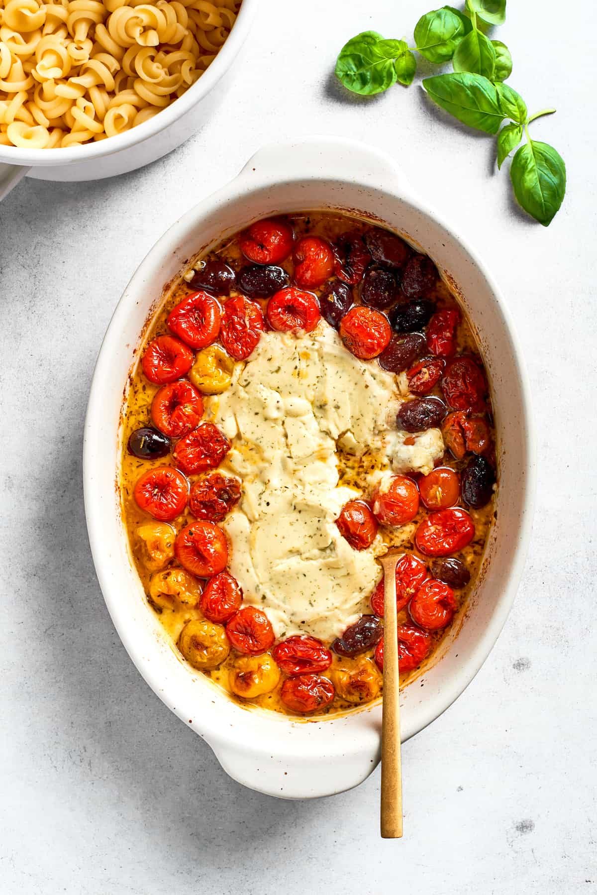 A spoon stirs the melted cheese into the tomatoes.