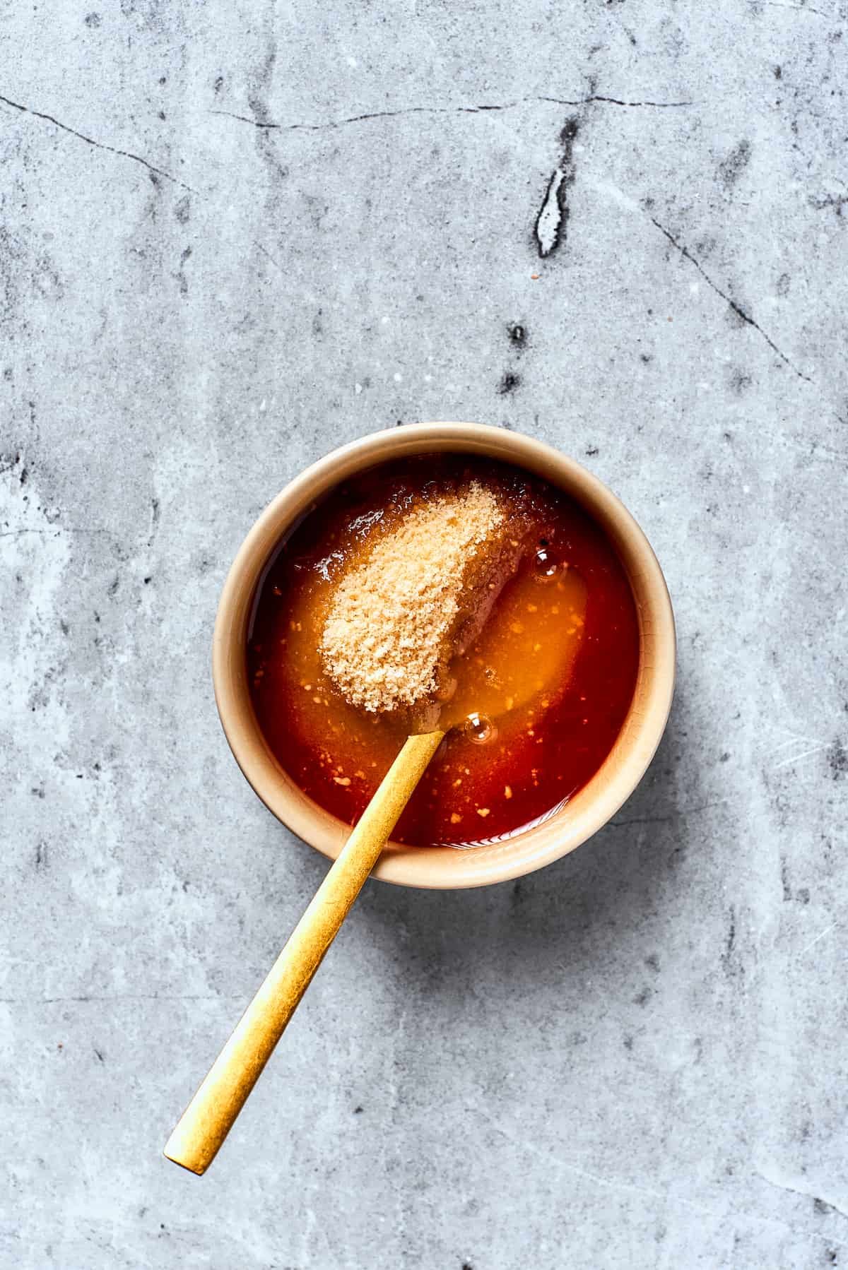 A spoon mixes brown sugar with ketchup and apple cider vinegar to make a meatloaf glaze.