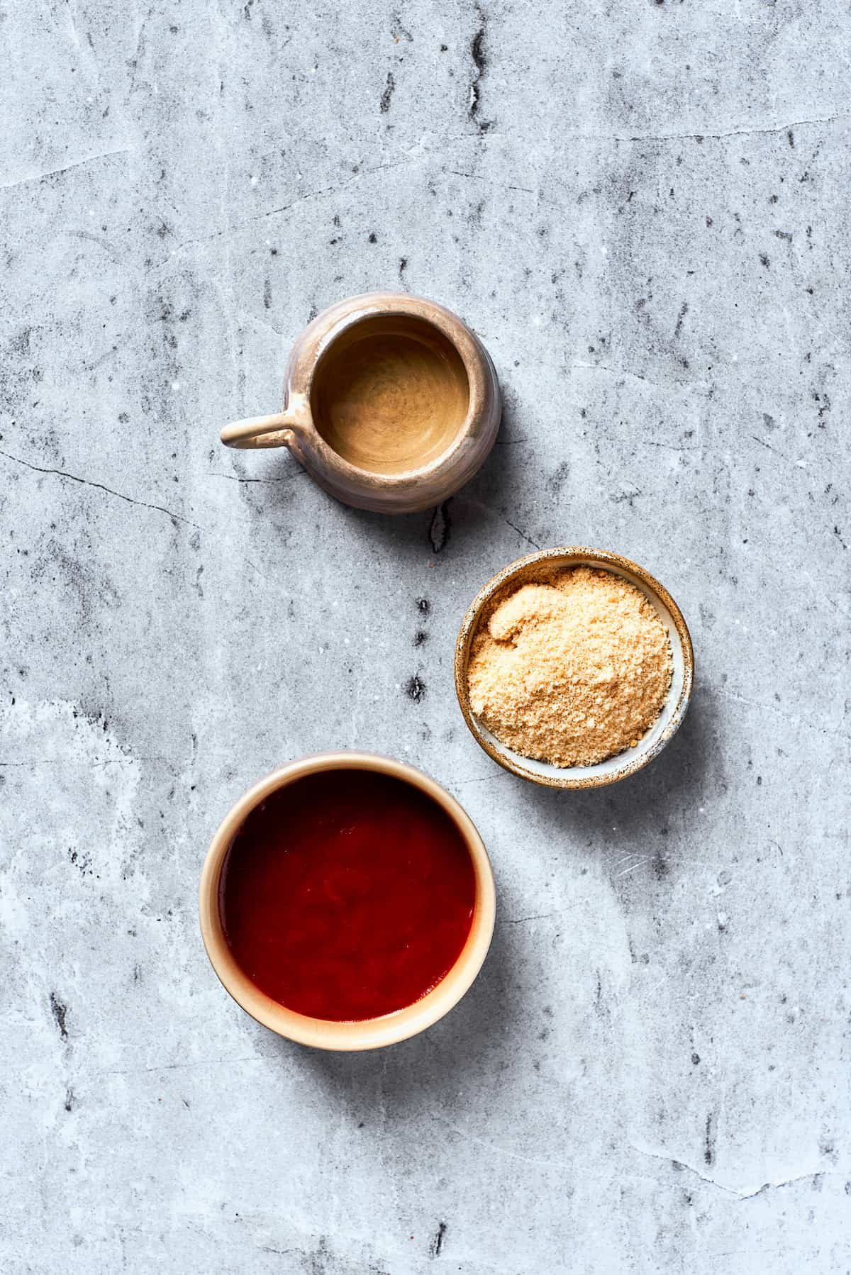 Brown sugar, ketchup, and apple cider vinegar are portioned into bowls.