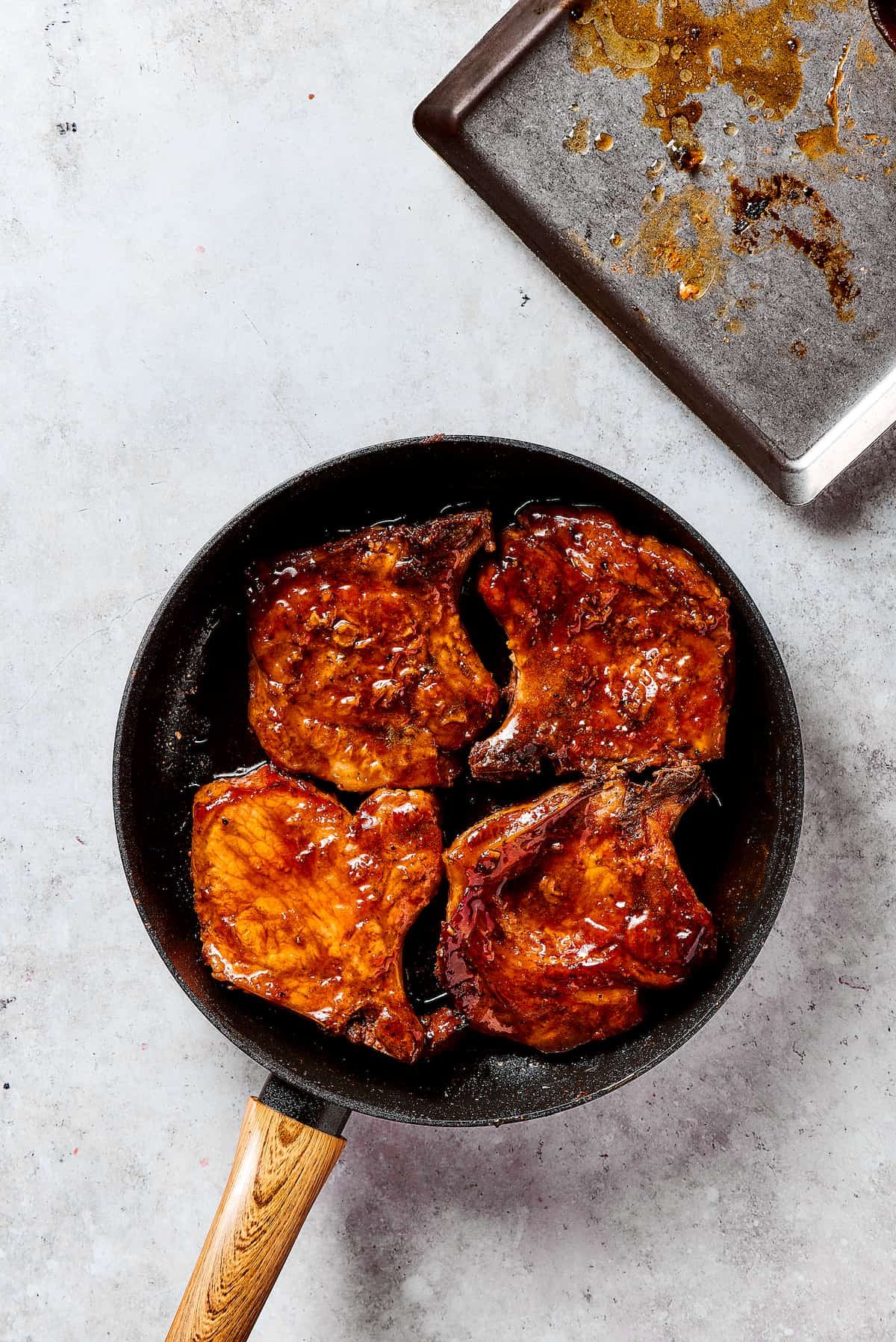 Glazing the pork chops in the brown sugar sauce.