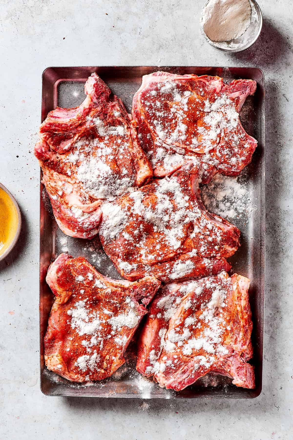 Pork chops sprinkled with seasoned flour.