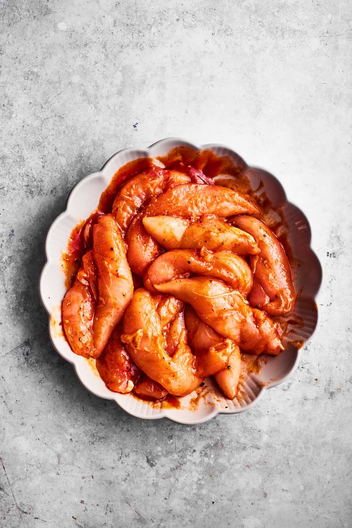 Chicken tenders turn red after being seasoned with hot sauce.