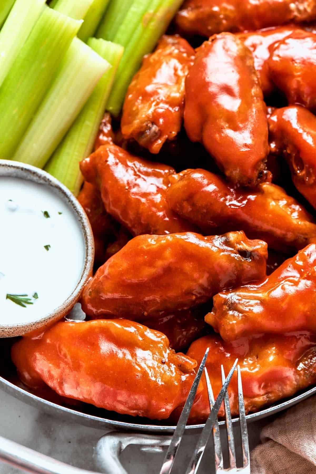 Buffalo wings in a dish with dipping sauce and celery.