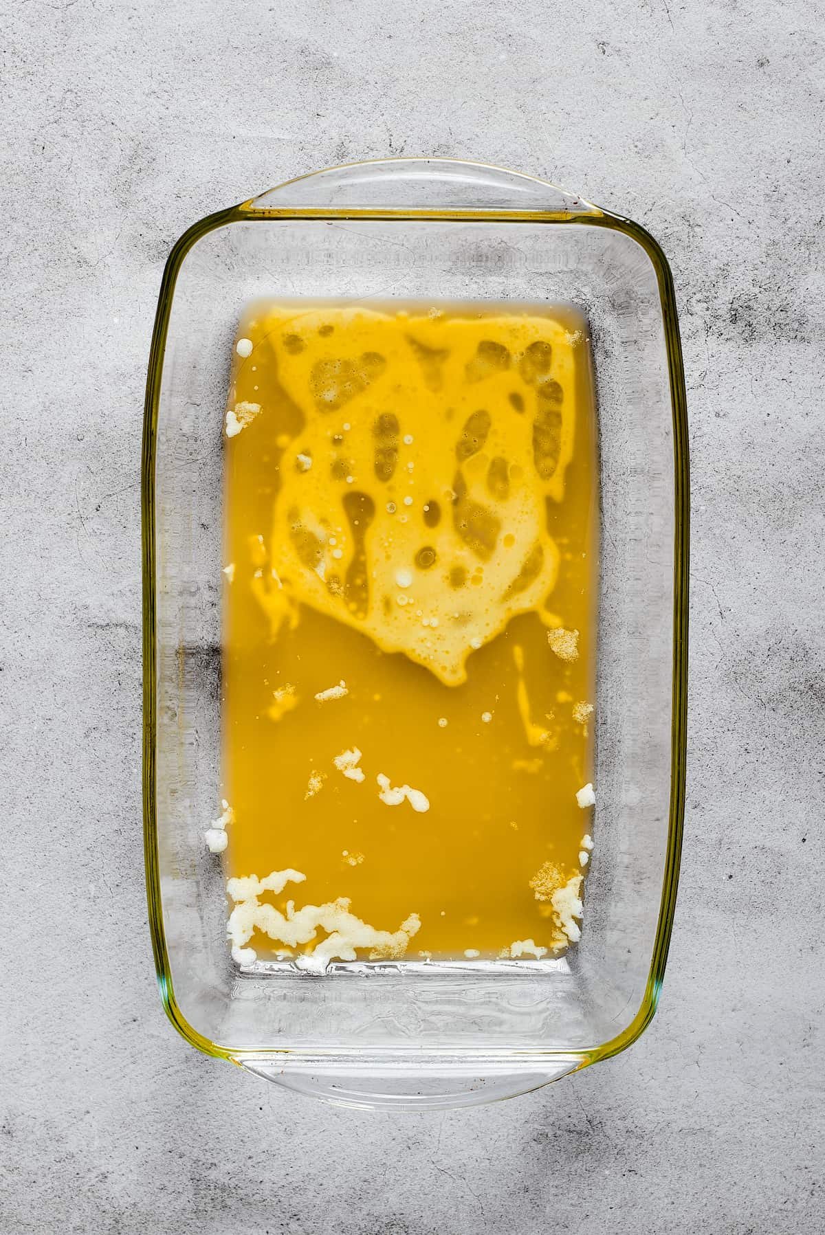 A rectangular baking dish with melted butter in it