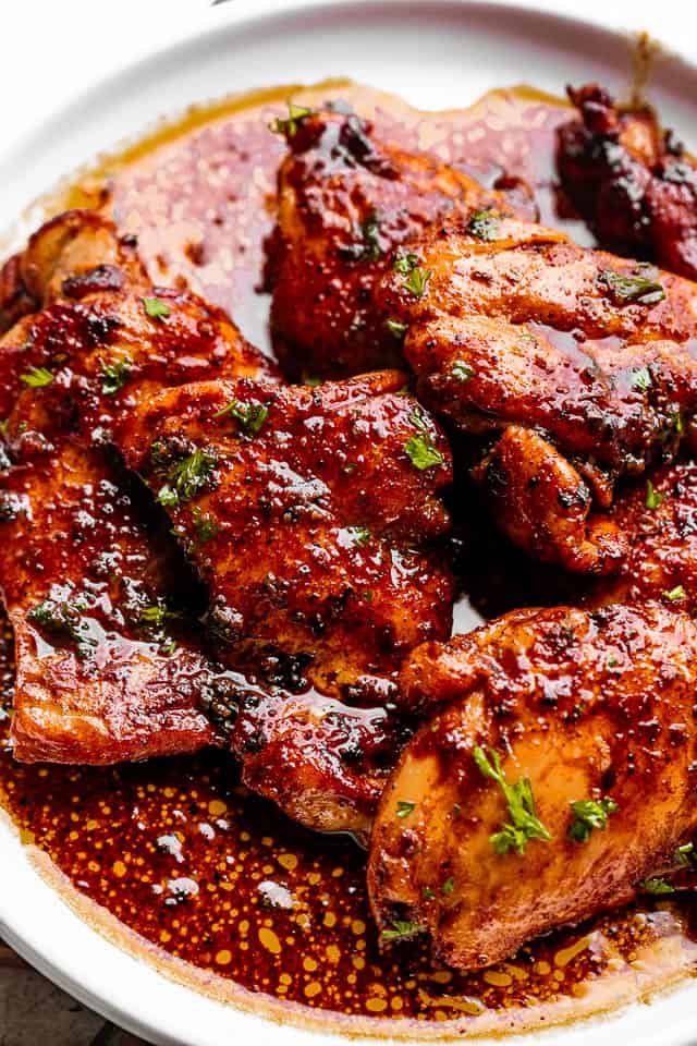 chicken thighs on a white plate topped with cajun flavored sauce
