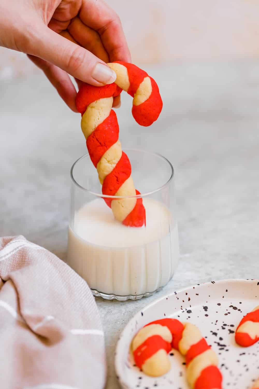 A Candy Cane Cookie Being Dipped into a Cold Glass of Milk