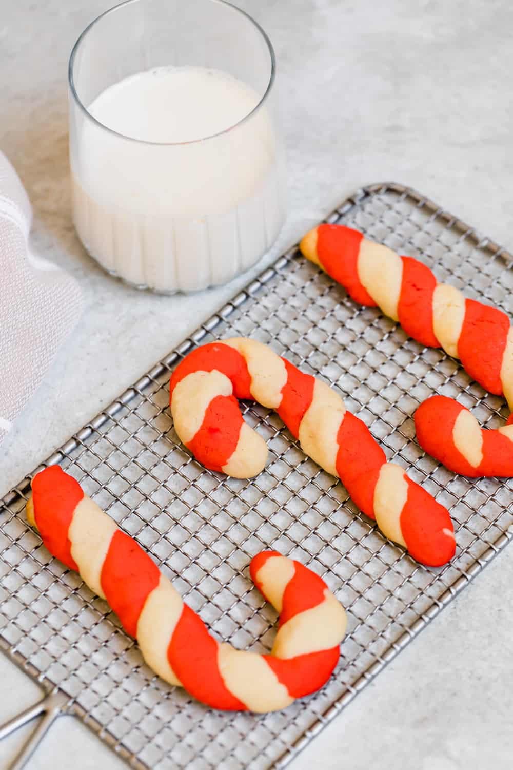 Three Candy Cane Cookies on a Granite Countertop Next to Santa's Milk