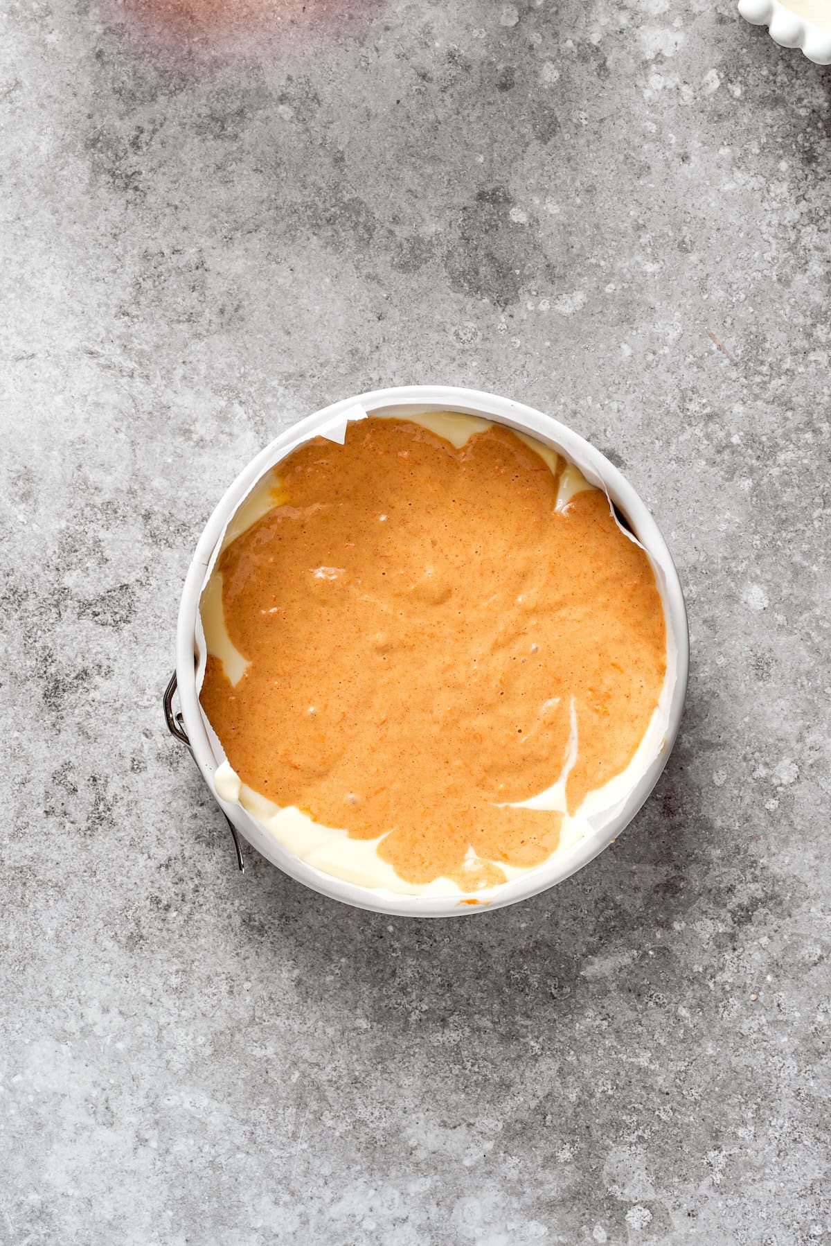 A layer of carrot cake is placed in a cake pan.