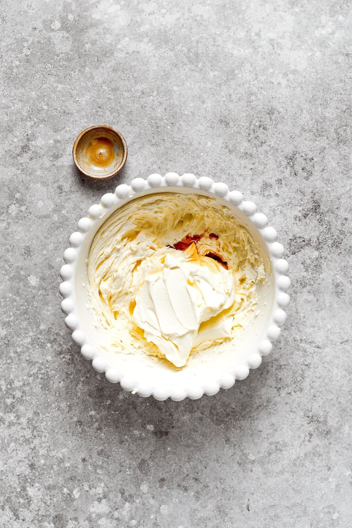 Vanilla is added to a bowl of cream cheese frosting.