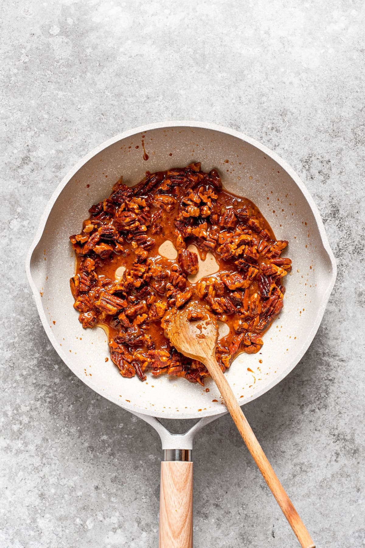 Pecans are toasted with butter in a skillet.