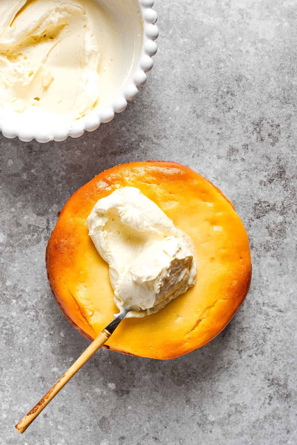 Cream cheese frosting is spread on the top of a carrot cake cheesecake,