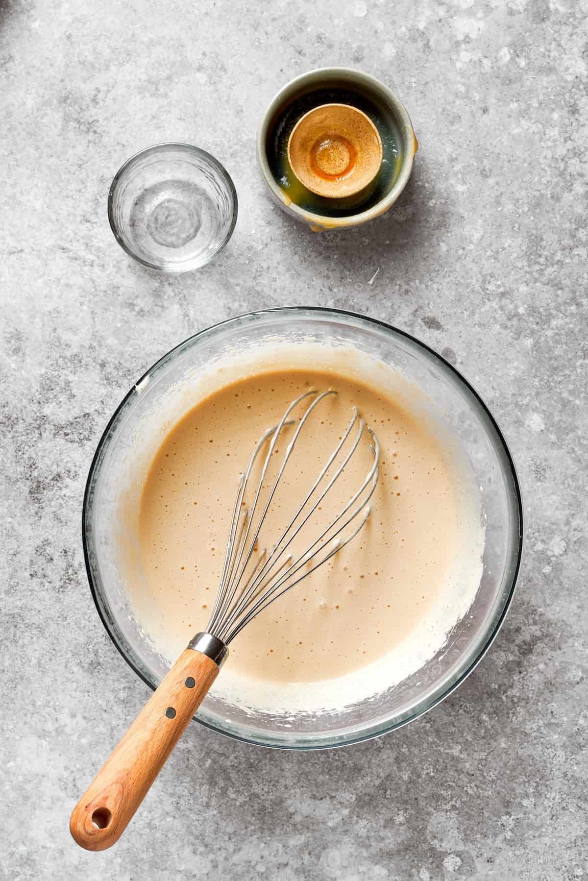 A whisk mixes the wet ingredients for carrot cake.