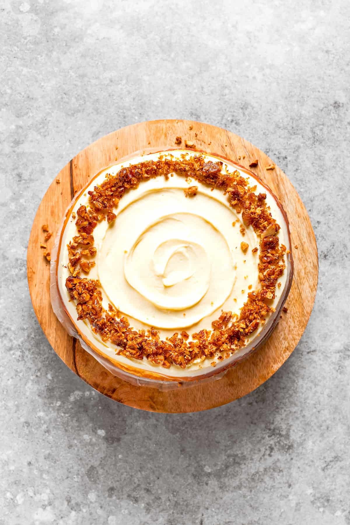 A carrot cake cheesecake on a wooden cake stand.