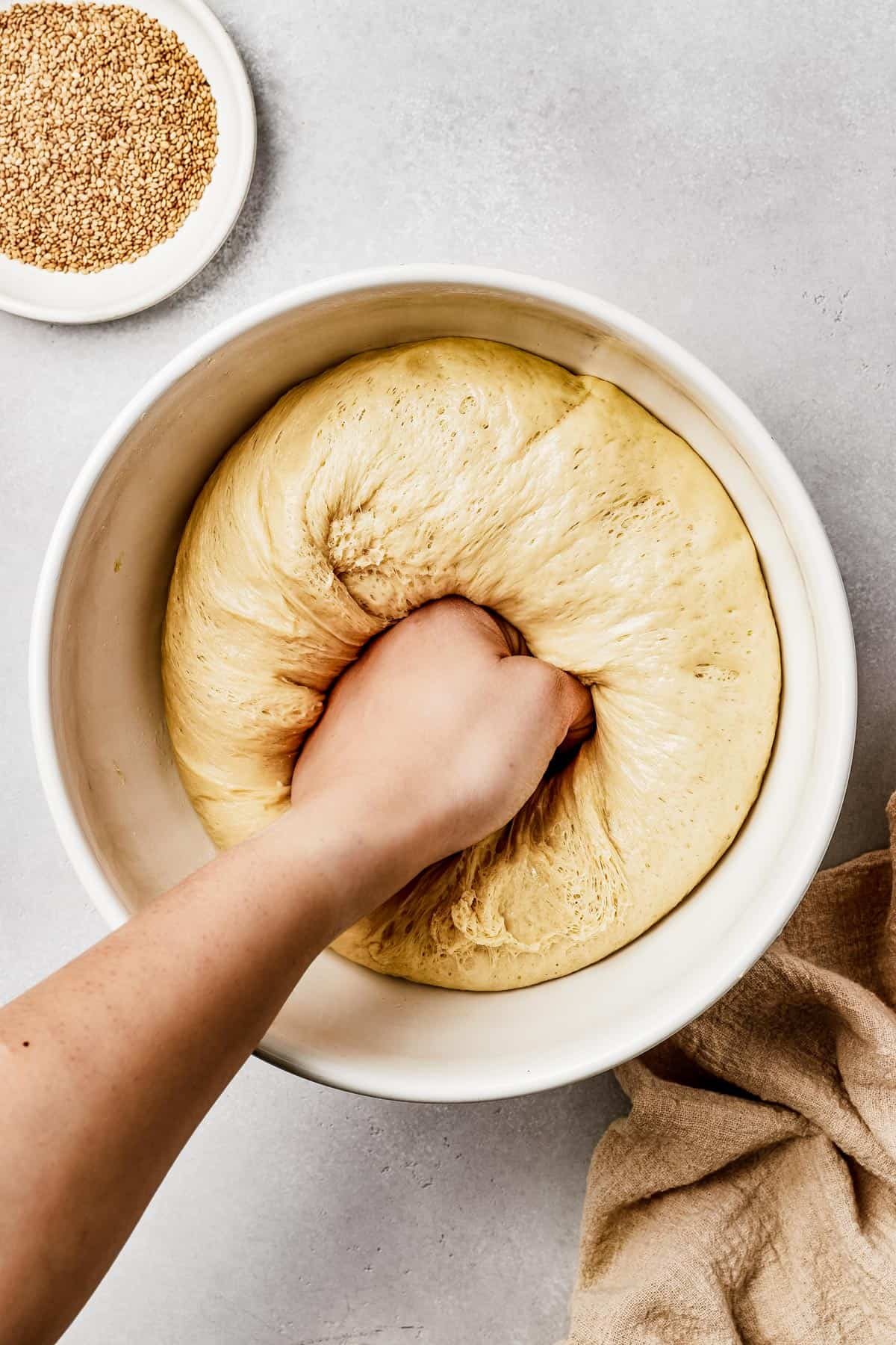 Risen bread dough being punched down in the center.