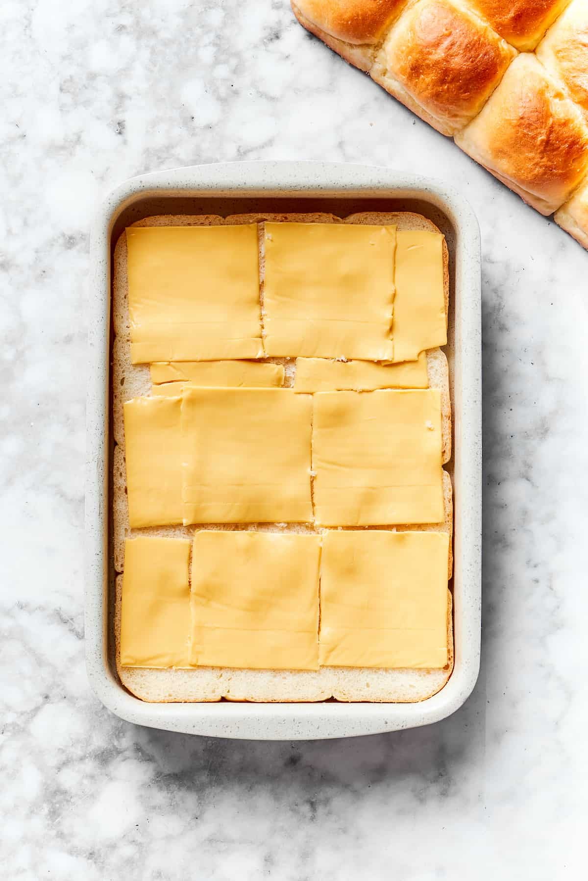 Slices of cheese are placed on top of rolls.