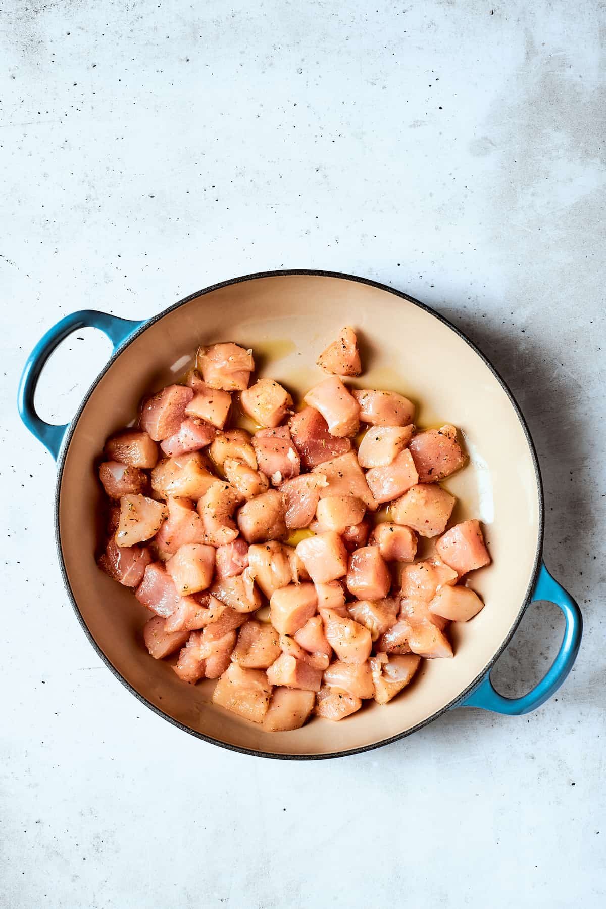 Pieces of chicken cook in a pot.