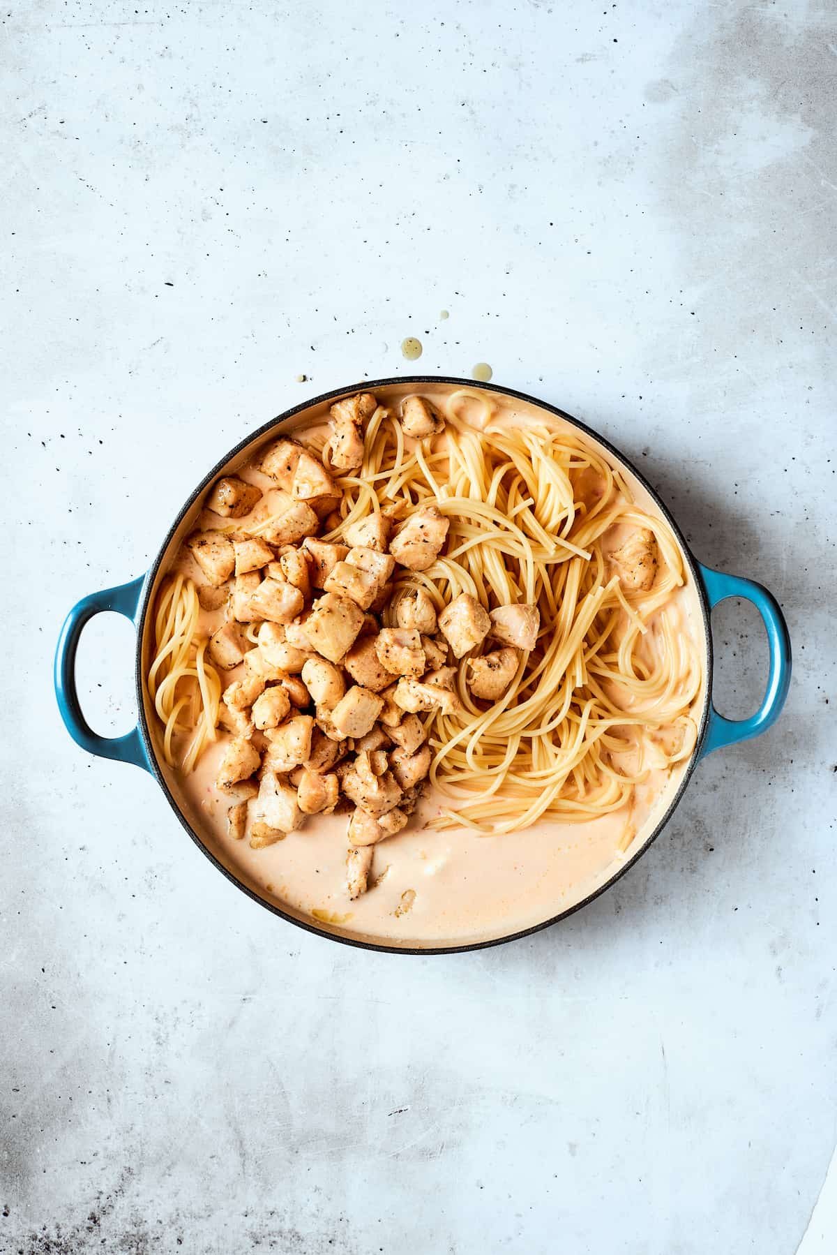The cooked chicken and spaghetti are added to the sauce.