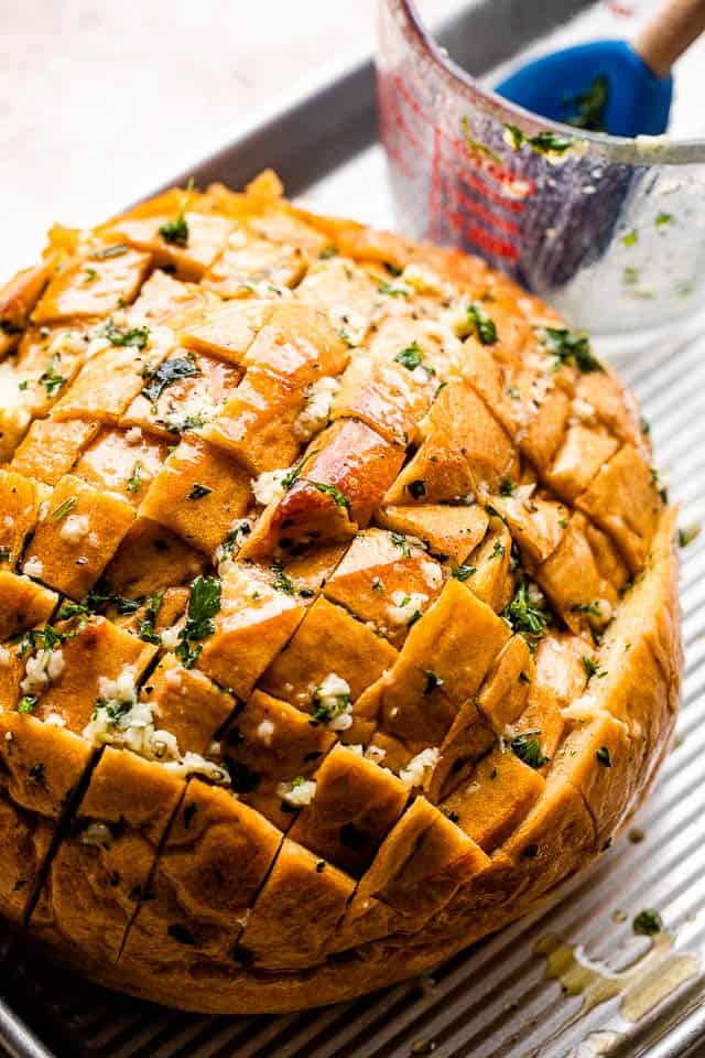 crosshatched loaf of bread with melted butter, garlic, and parsley
