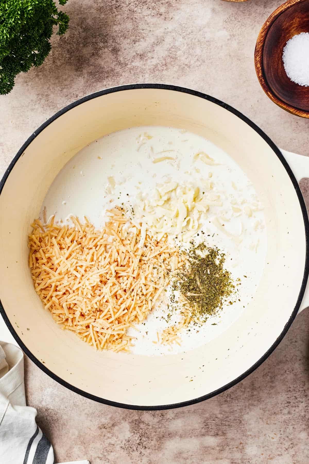 Alfredo sauce being whisked in a large pot.
