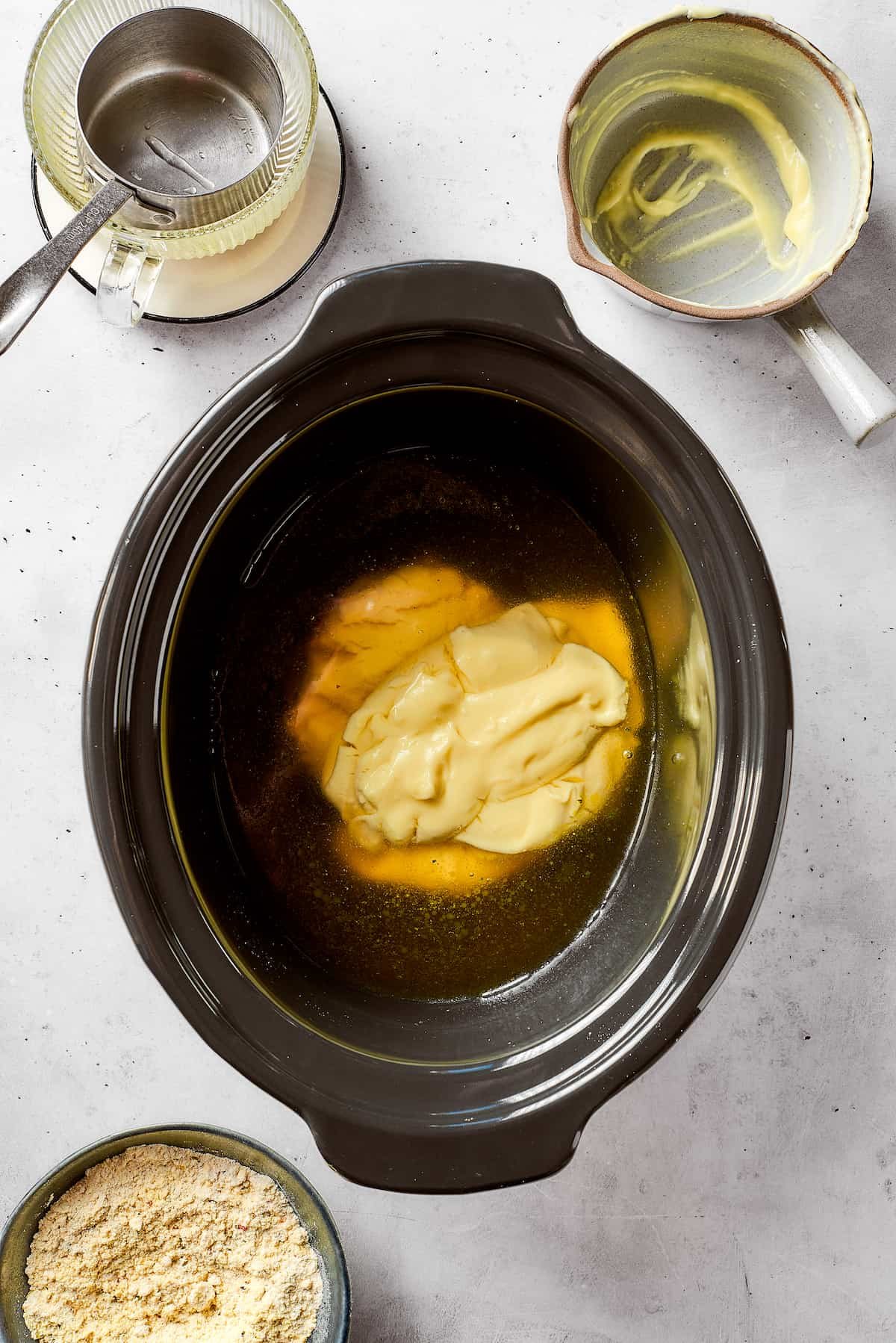 Chicken broth and cream of chicken soup are placed in a slow cooker.