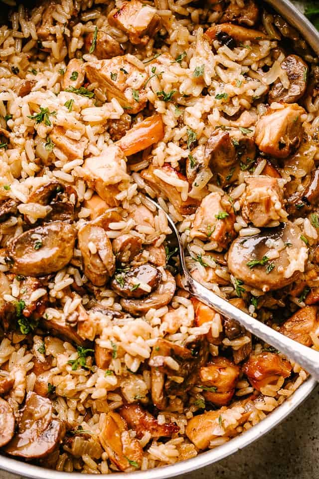 Chicken and mushrooms sauteing in a pan with rice