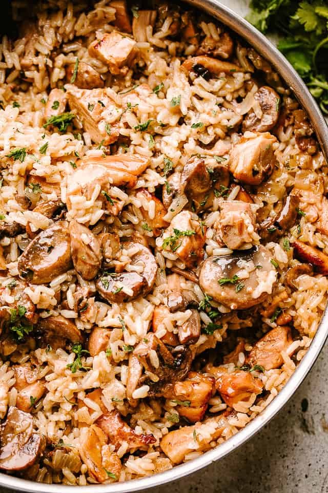 A close-up of rice tossed with chicken pieces and mushrooms.