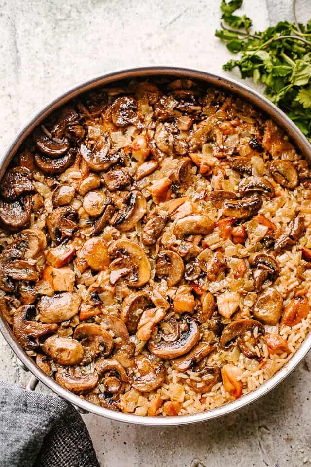 Cooking mushrooms with rice in a pan.